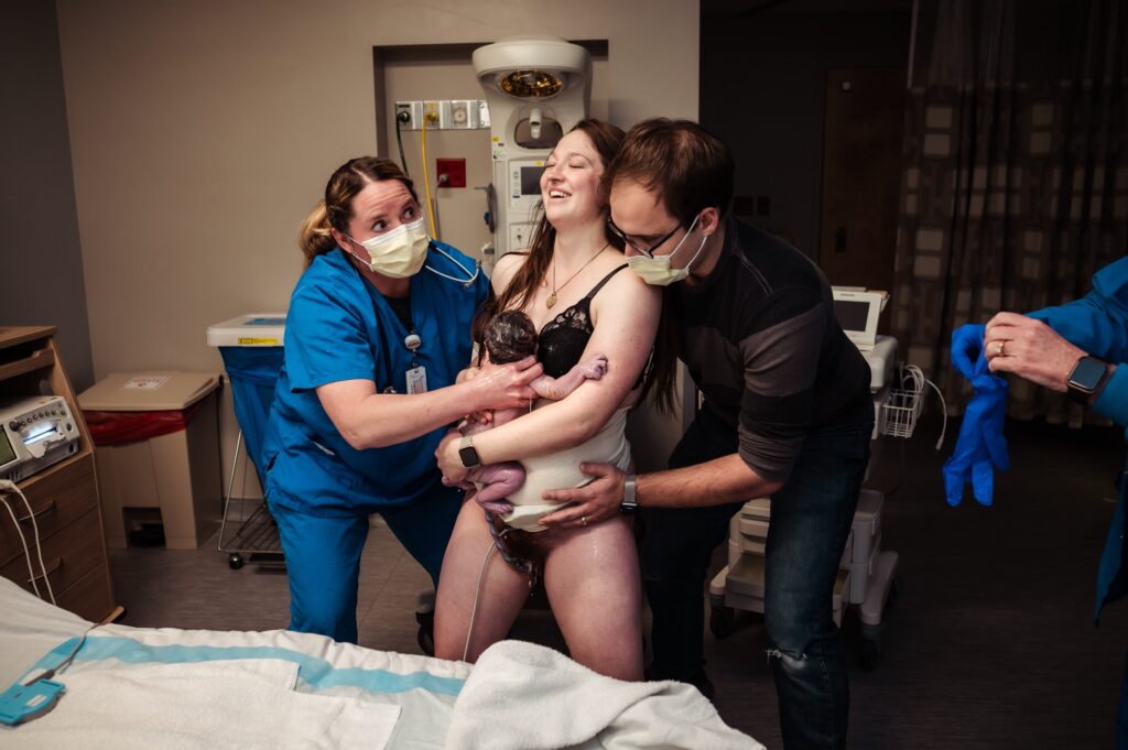 Kaitlyn births and catches her babe standing next to the hospital bed at a Utah hospital.
Credit: Wild Oak Birth