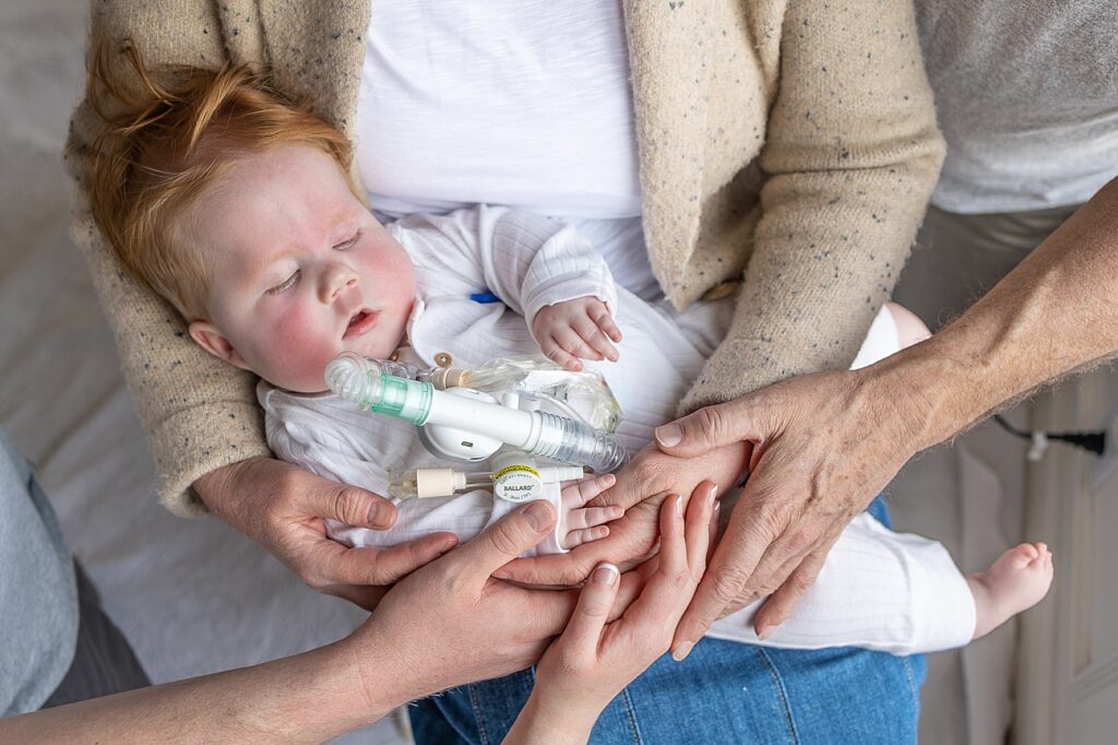 Little Cal is held by his grandma, with his grandpa and parents' supporting hands